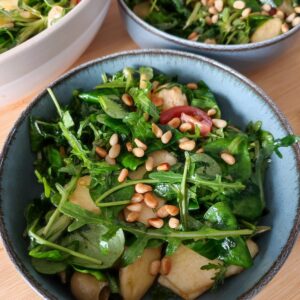 The Everything Salad portioned between two blue bowls with the large bowl of leftover salad in the background on a working surface