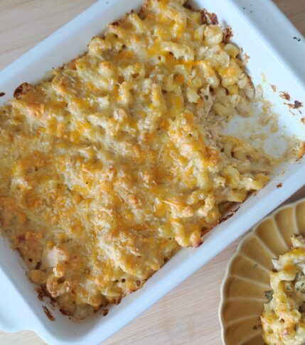 Classic Baked Mac & Cheese in a casserole dish with a chunk of it in the corner taken off