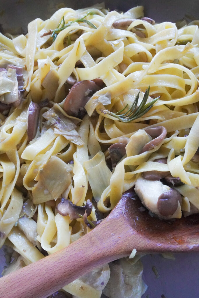 B roll 2 : One Pan Lemon Butter Tagliatelle with Mushrooms & Artichokes in a pan with a wooden spatula on the side