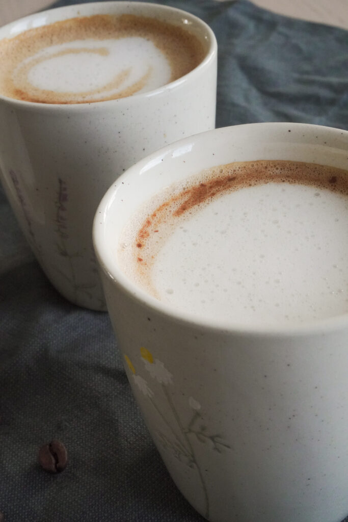 B roll 2: Dubai Chocolate Inspired Mocha in two cups with a single coffee bean on the side on a dark green fabric from a side shot closeup