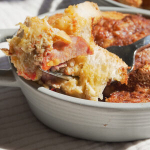 Breakfast Strata with a forkful of it on the side and another breakfast strata can be seen in view partially at the back