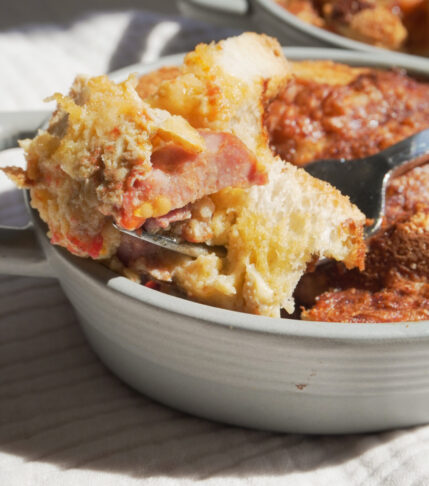 Breakfast Strata with a forkful of it on the side and another breakfast strata can be seen in view partially at the back