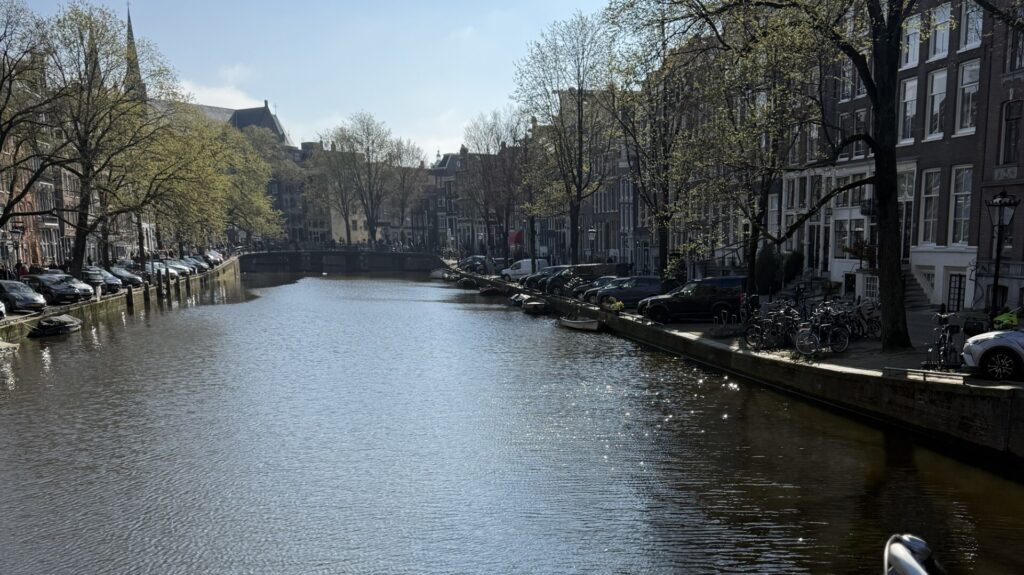Sunlight sparkling on a canal with trees and bicycles on a bridge