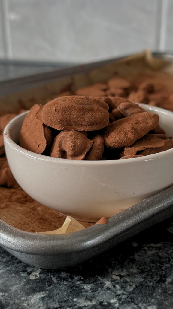 A full bowl of Pecan Truffles on a tray full of remaining Pecan Truffles