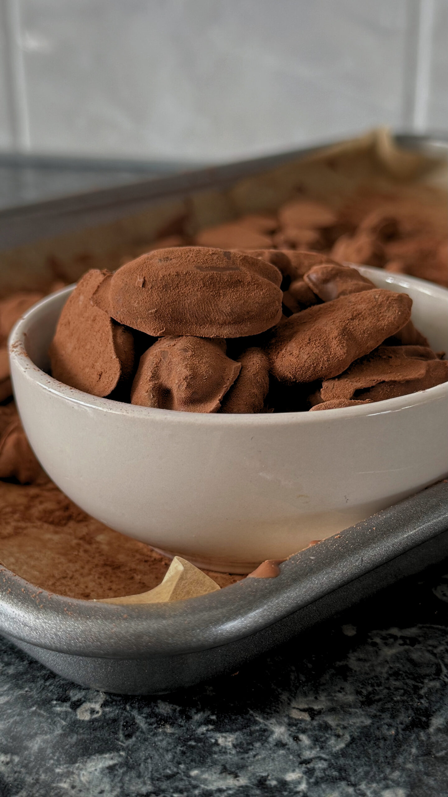 A full bowl of Pecan Truffles on a tray full of remaining Pecan Truffles