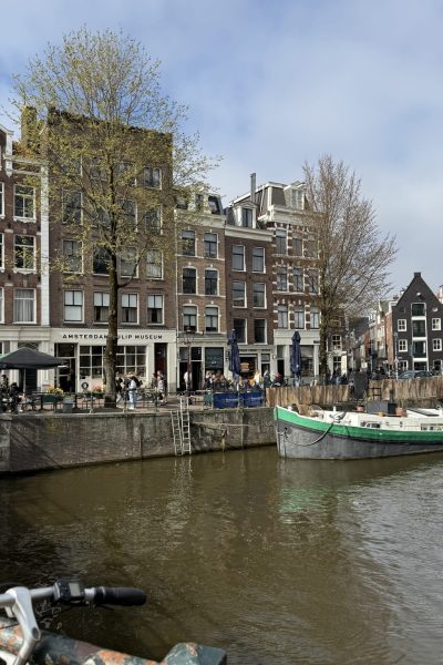 Canal lined with trees and buildings with a green boat passing by